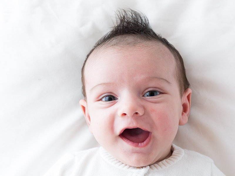 A portrait of a newborn smiling on white background.
Un neonato sorride su sfondo bianco e luminoso.