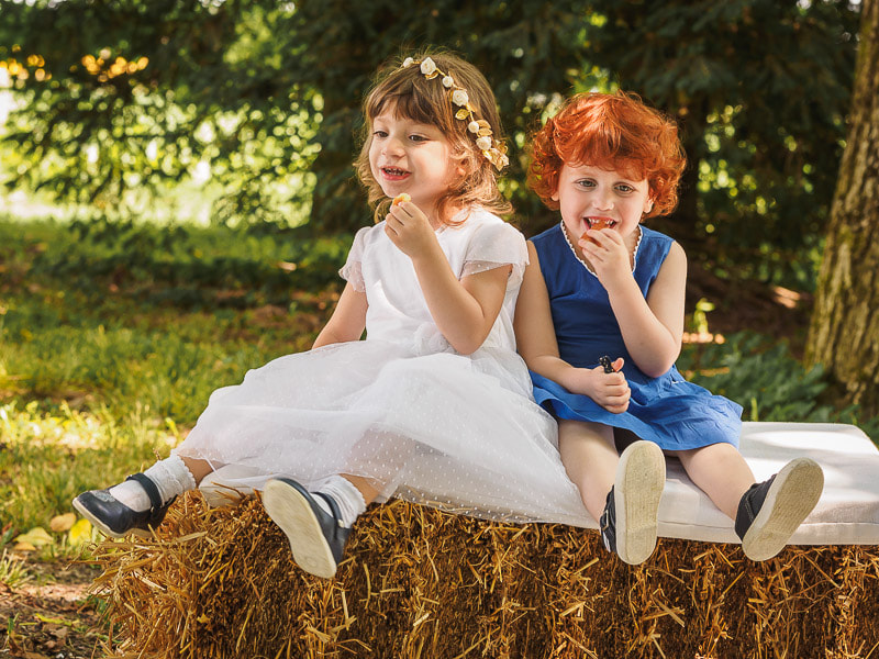 Two young little girls sitting on a bale of hay in countryside.
Due bambine sedute su una balla di fieno in campagna.